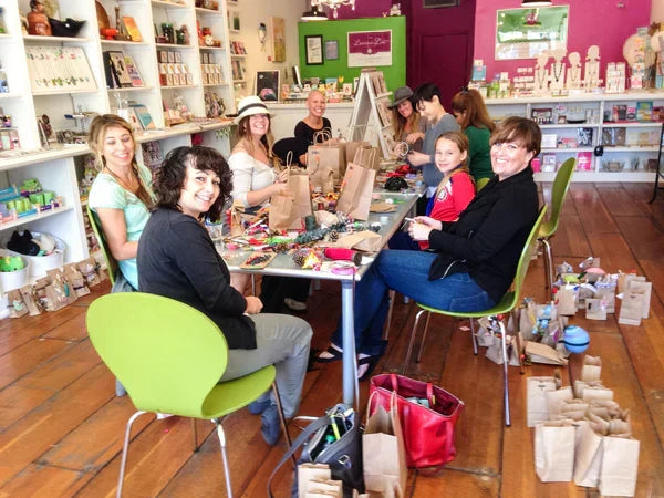 Photo of nine kids and adults at a table in Leanna Lin's Wonderland participating in an advent calendar crafting workshop.