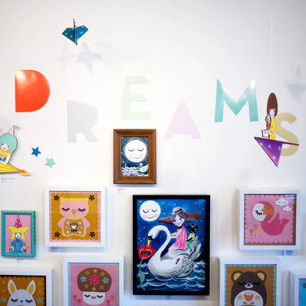 Photo of gallery wall from the "Dreams" art show. Art is all very cute pinks and pastel colors of sleeping or dreaming characters.