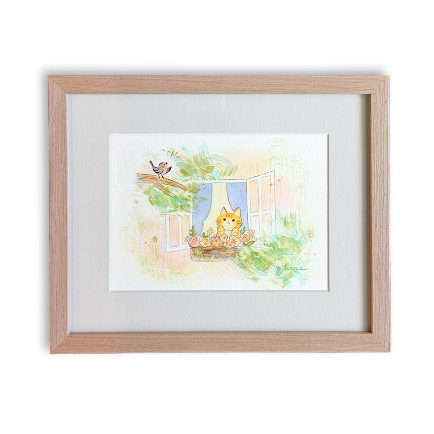 A framed watercolor art print featuring a cute orange cat sitting on a windowsill with a flower basket, a small bird on a branch, and soft pastel green foliage, set in a light natural wood frame with a white mat.