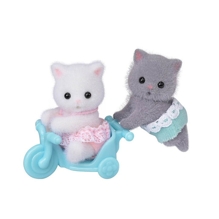 A white flocked cat figurone in a pink outfit sitting in a light blue bicycle cart, with a gray kitten in a mint green outfit pushing it, on a solid white background.