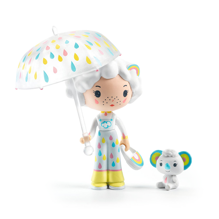 A toy figurine with pale, freckled skin and white hair carrying an umbrella and purse outfitted with pastel-colored raindrops and rainbows. To her side, a small white panda with a blue nose. Figurines are displayed on a white background. 