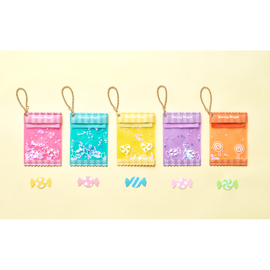 Five mini-figure keychain pouches with gold loops, shown in pink, blue, yellow, purple. and orange, arranged on a pale yellow background with matching candy-shaped cards below.