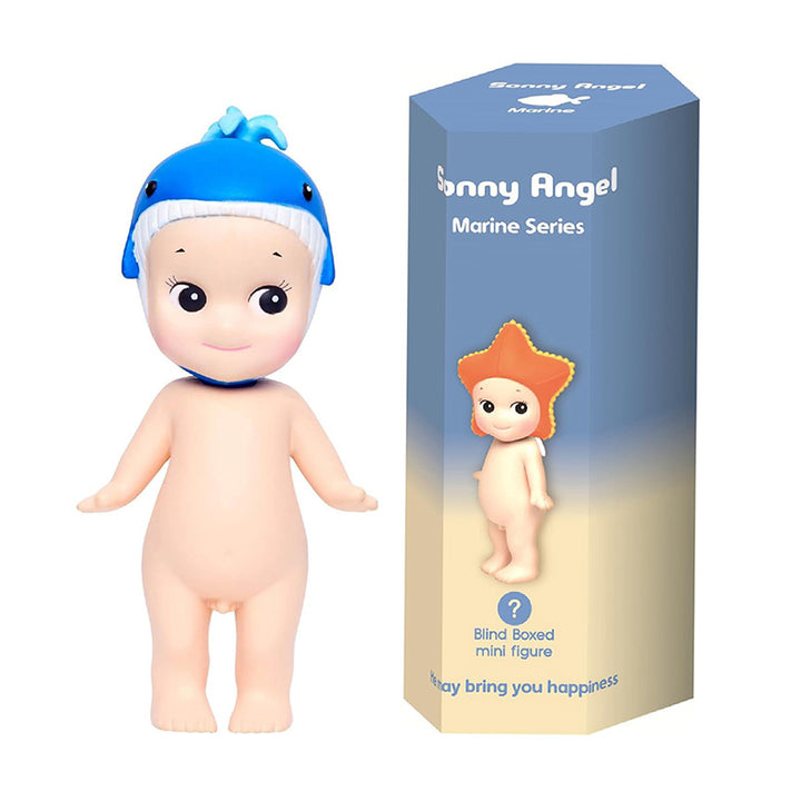 Toy figurine of a baby angel with a blue whale hat next to its packaging on a white background.