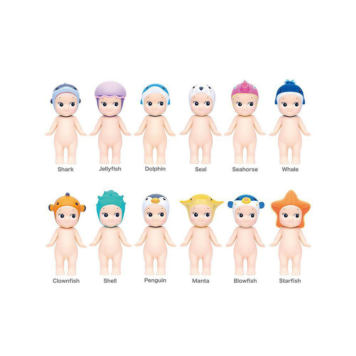 Set of 12 small figurines with colorful marine animal hats, labeled; shark, jellyfish, dolphin, seal, seahorse, whale, clownfish, shell, penguin, manta, blowfish, and starfish; on a white background.