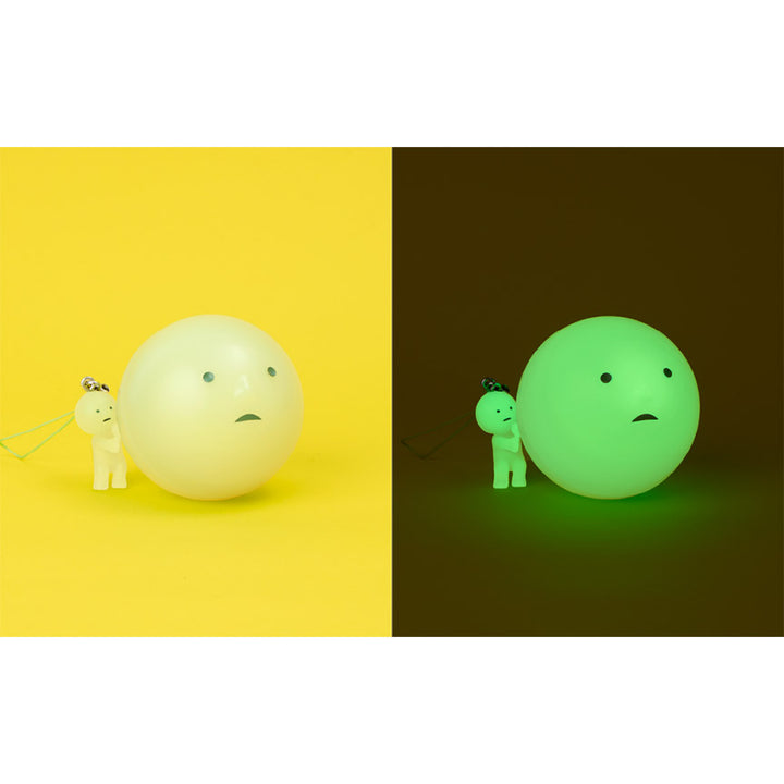 Smiski keychain and ball packaging shown in regular lighting on the left and glow-in-the-dark on the right.