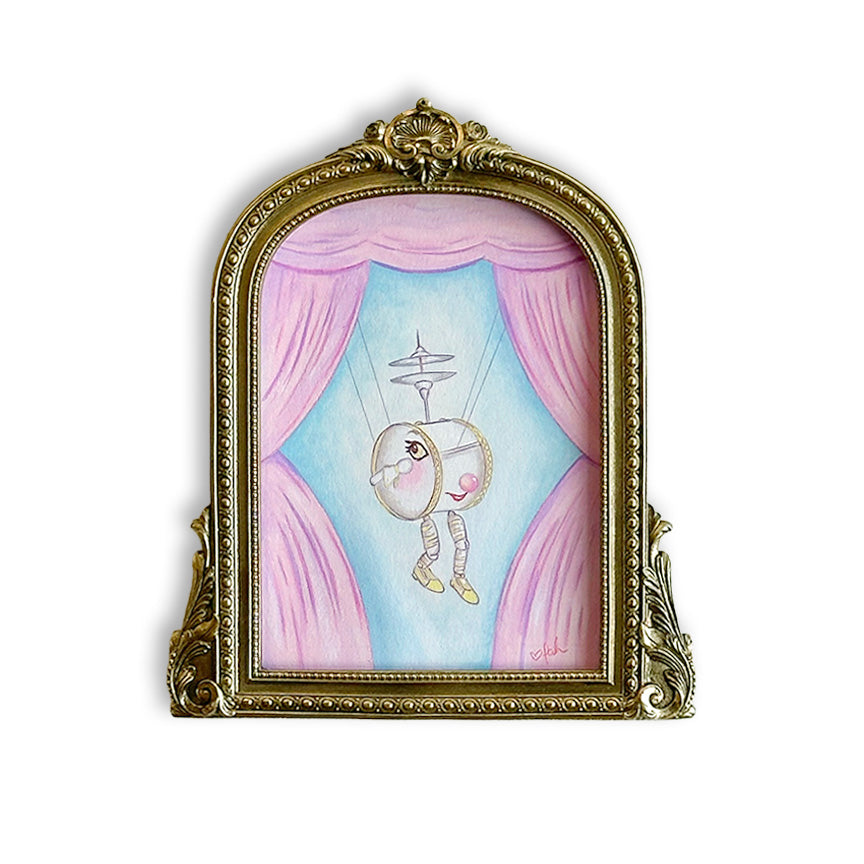 A framed whimsical painting featuring a drum-shaped marionette in front of pink curtains and a light blue background, enclosed in an ornate gold frame on a white background.
