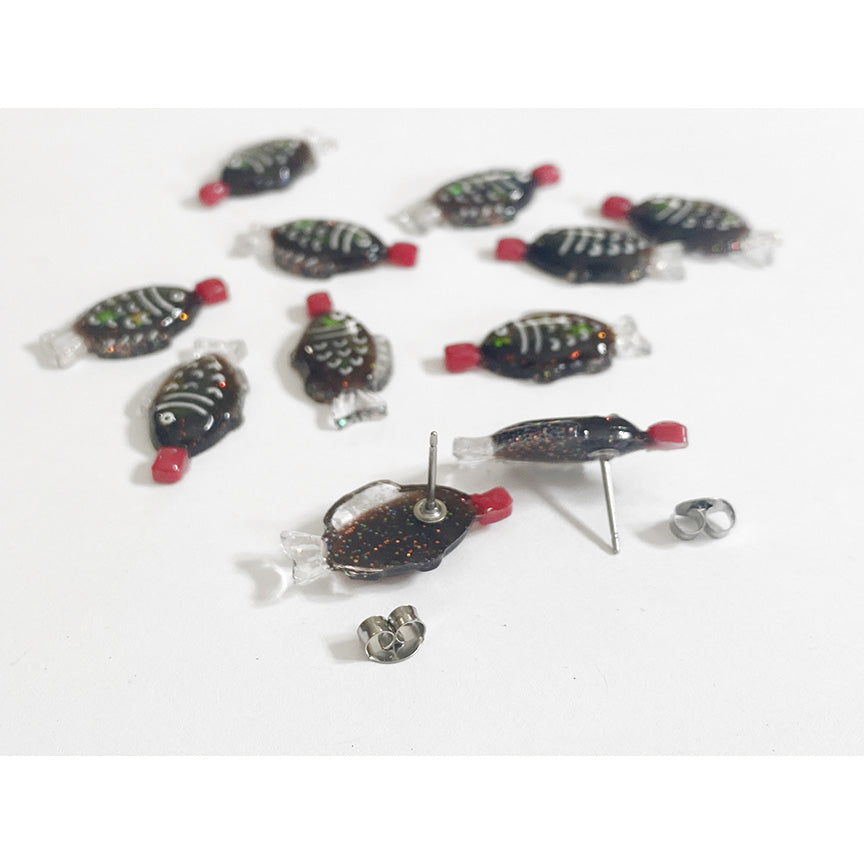 Several pairs of f fish-shaped soy sauce packet stud earrings, one pair flipped upside down so you can see the metal stud backings. 