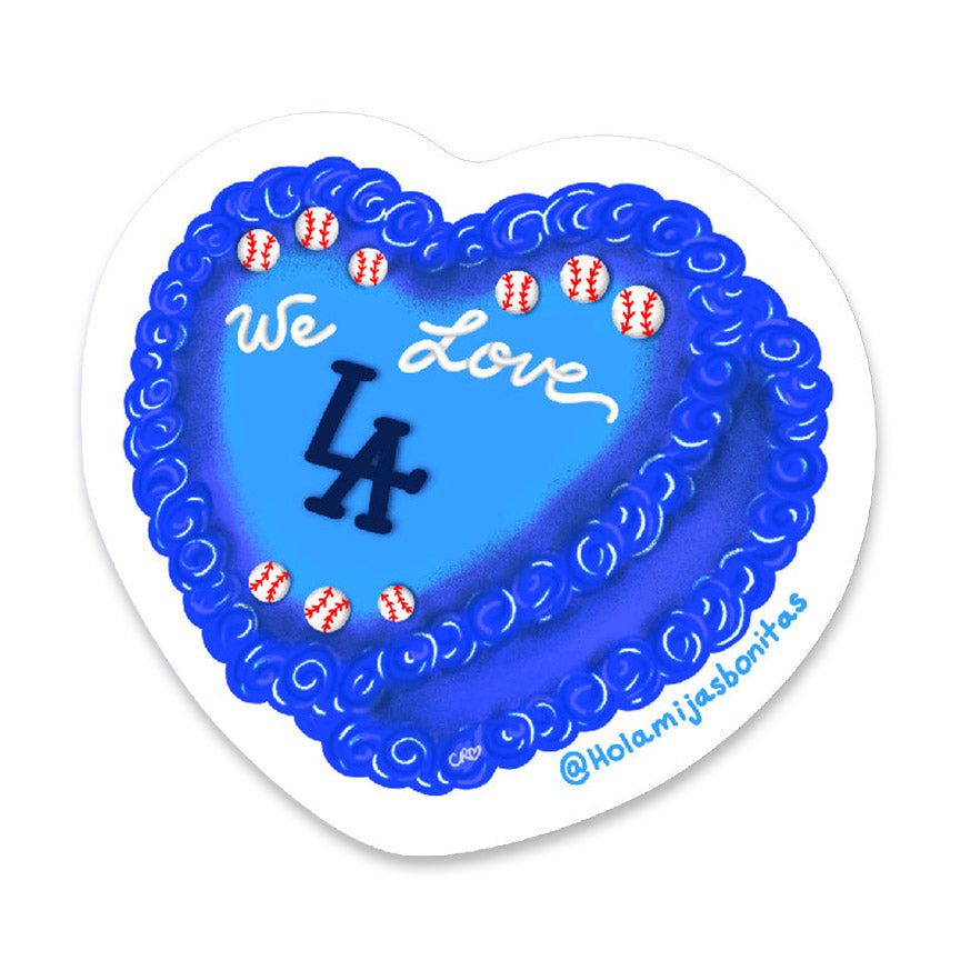 Heart-shaped blue cake sticker with 'We Love LA' text in icing and baseball decorations on a white background.