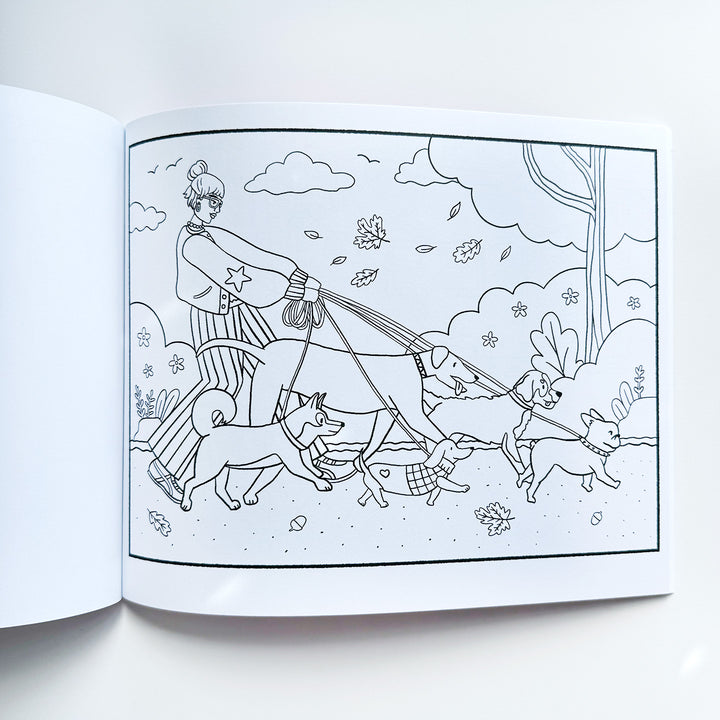 Black  and white line drawing coloring page featuring an image of a girl with an updo and trendy clothing, walking five different dogs of varying sizes in a park. Park is fall-themed with leaves and acorns. 