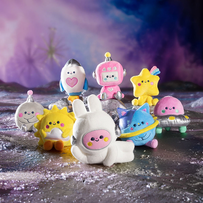 Picture of nine varying plush designs possible in blind box, including a secret design only half shown. All characters are space themed with designs like stars, planets, ships, and more. Characters are on a planet-like background.