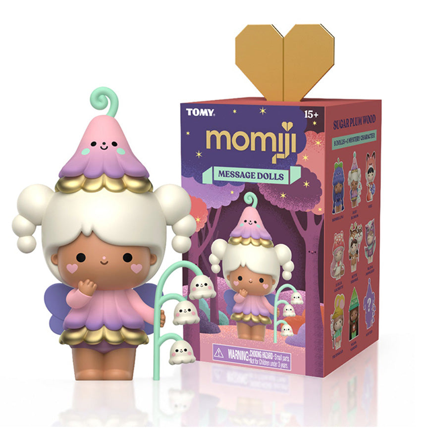 A Momiji Message Doll blind box featuring a cute pastel Momiji doll with white hair, a pink and purple flower hat, and a small green flower accessory, shown next to its purple packaging box with a gold heart-shaped flap.