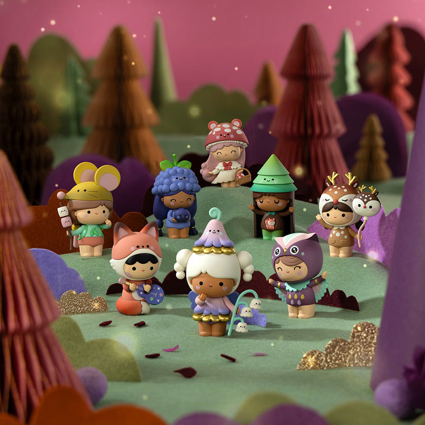 A group of cute, stylized Momiji figurines dressed in whimsical animal and nature outfits, arranged in a miniature forest scene with layered paper-cut trees and hills. 
