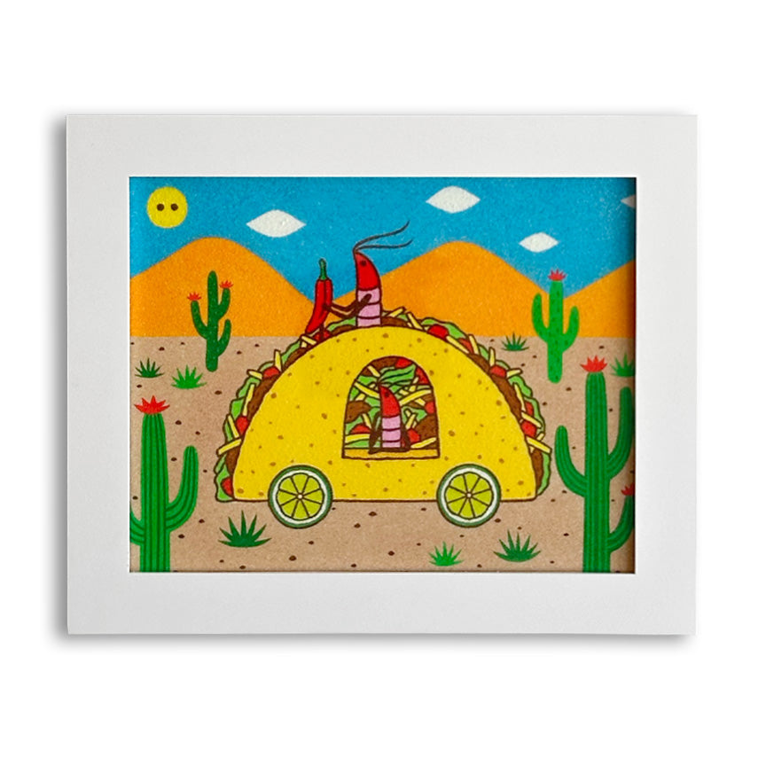 A framed art piece featuring a shrimp character behind a steering wheel shaped like a pepper, driving a car shaped like a taco. There is another shrimp looking out the car window and the wheels are limes. They are driving through a desert landscape with a blue sky and orange mountains. The piece is shown in a white frame against a a white background.