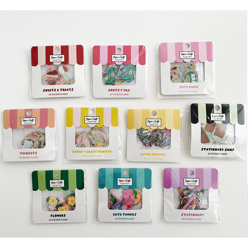Ten small packaged sticker sets arranged in a grid on a white background. Each package has a colorful striped awning-style header and a clear window showing assorted themed stickers.