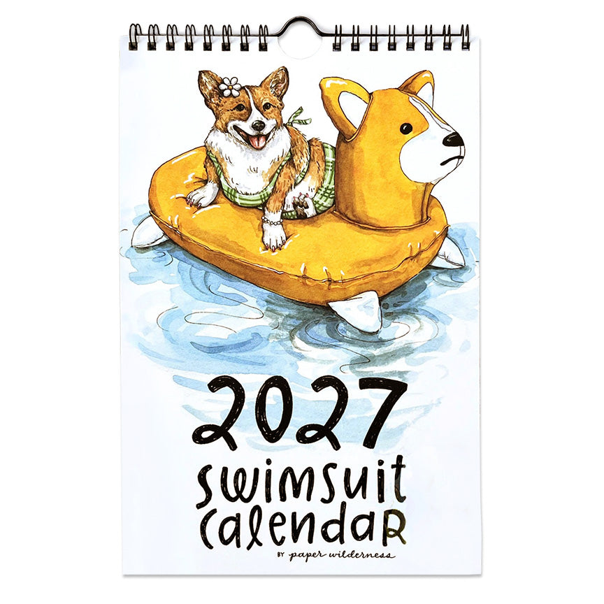 The front of a 2027 Animal Swimsuit Calendar. Featuring a watercolor illustration of a corgi in a green swimsuit floating on a yellow corgi float, with a spiral binding at the top.