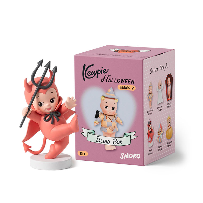 Kewpie figure next to it's packaging, titled "Kewpie Halloween Series 2". On the packaging is a picture of a small cherub figure wearing a scarecrow costume. The figure next to the box is another Kewpie cherub figure wearing a full red devil costume with tail and pitchfork. 