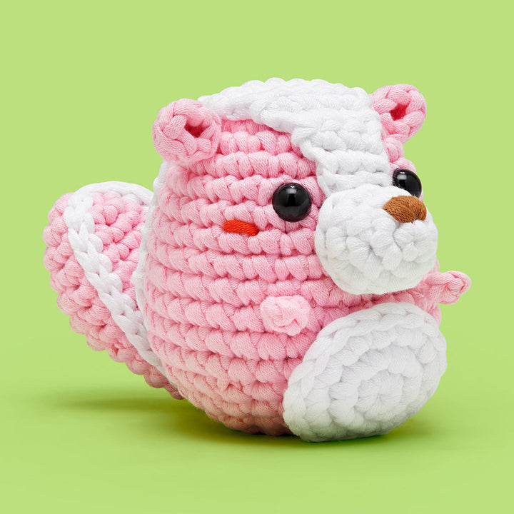 Finished crochet— a pink skunk with black plastic eyes, white stripe, white snout, and white belly with red cheeks. 
