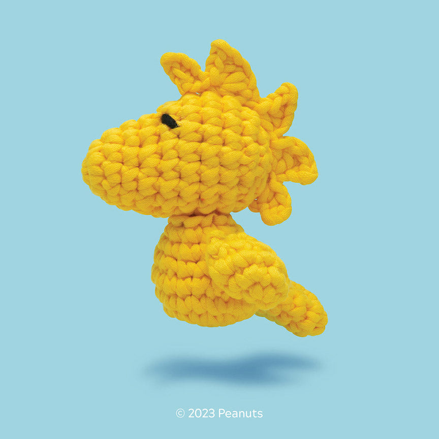 Yellow crocheted plush shaped like Woodstock on a blue background.