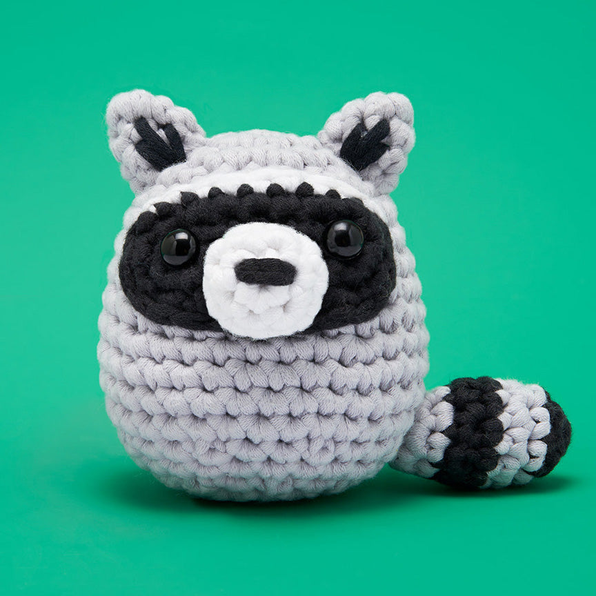 Finished crochet— a round black and gray raccoon with black plastic eyes. 