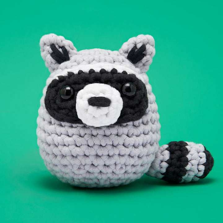 Finished crochet— a round black and gray raccoon with black plastic eyes. 