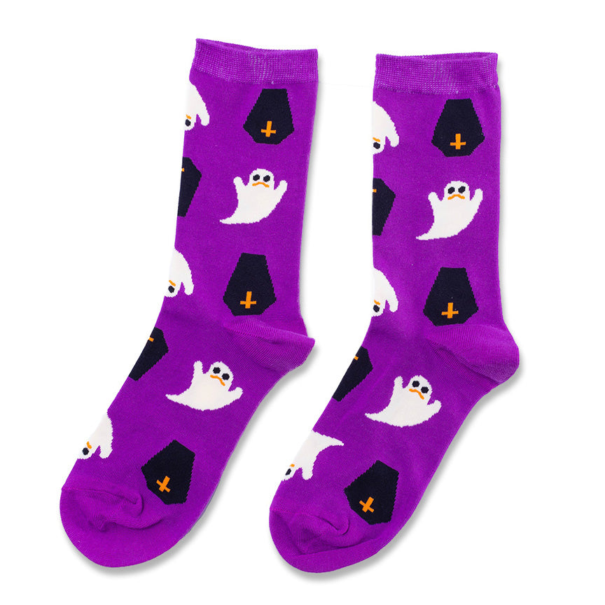 A pair of purple crew socks with a Halloween pattern featuring white ghosts and black tombstones with orange crosses, shown on a plain white background.