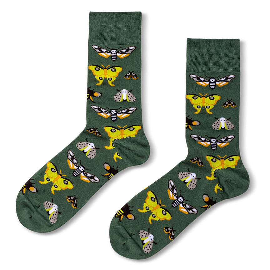 A pair of dark green crew socks featuring a repeating pattern of yellow, black, white, and orange moths, displayed against a plain white background.