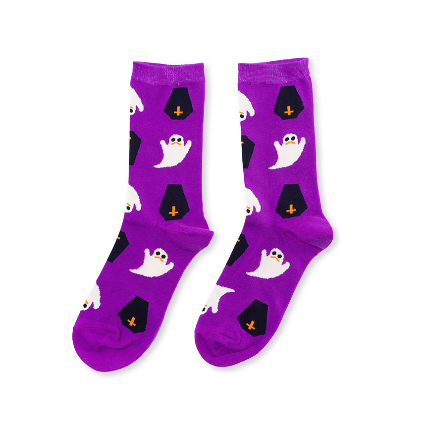 A pair of purple crew socks with a Halloween pattern featuring white cartoon ghosts and black tombstones with orange crosses, shown on a plain white background.