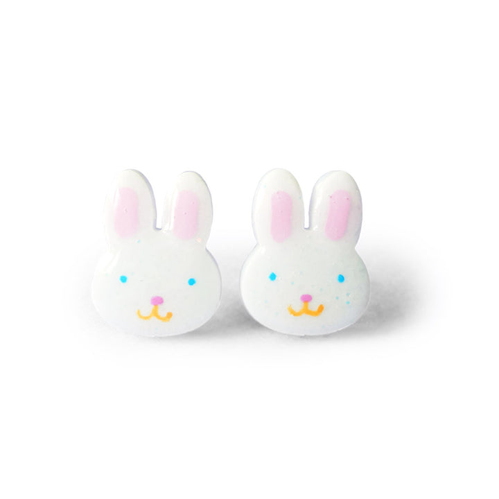 A pair of white rabbit-shaped stud earrings with pink inner ears, blue eyes, pink nose, and yellow smile.