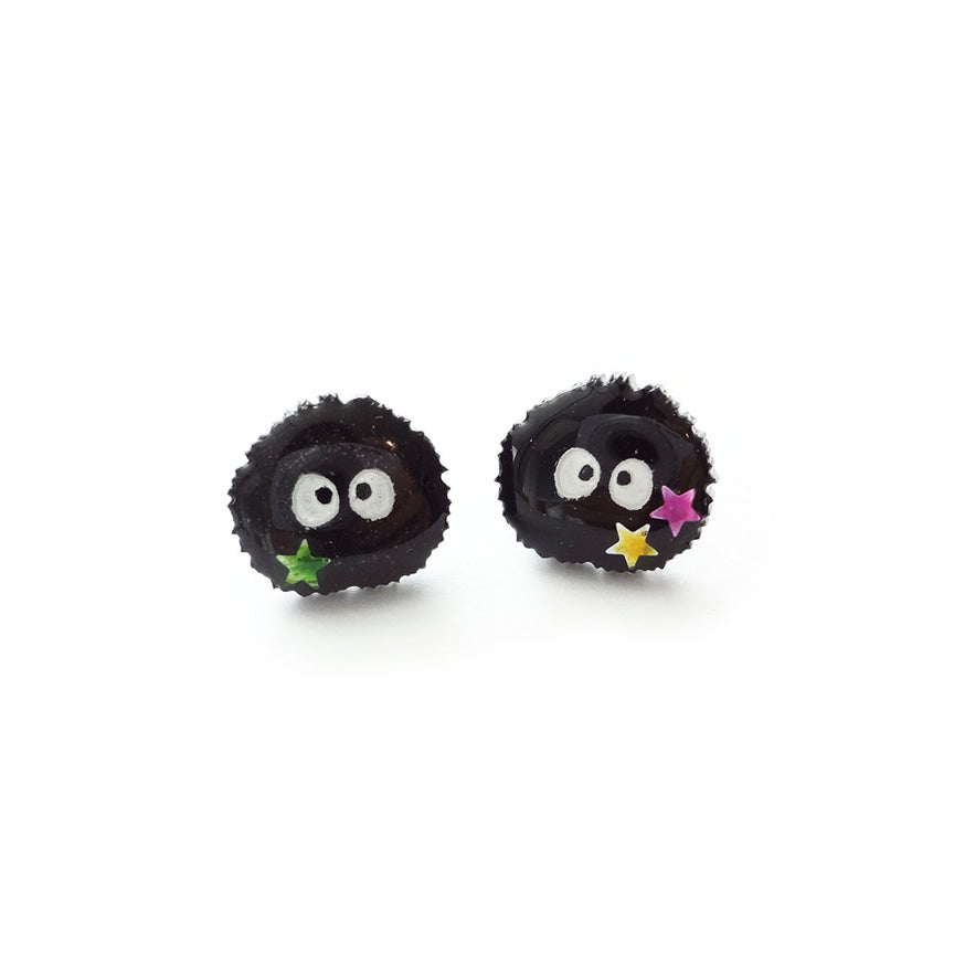 A pair of stud earrings in the shape of soot sprites, little black puff balls with eyes holding stars, from the movie "Spirited Away."