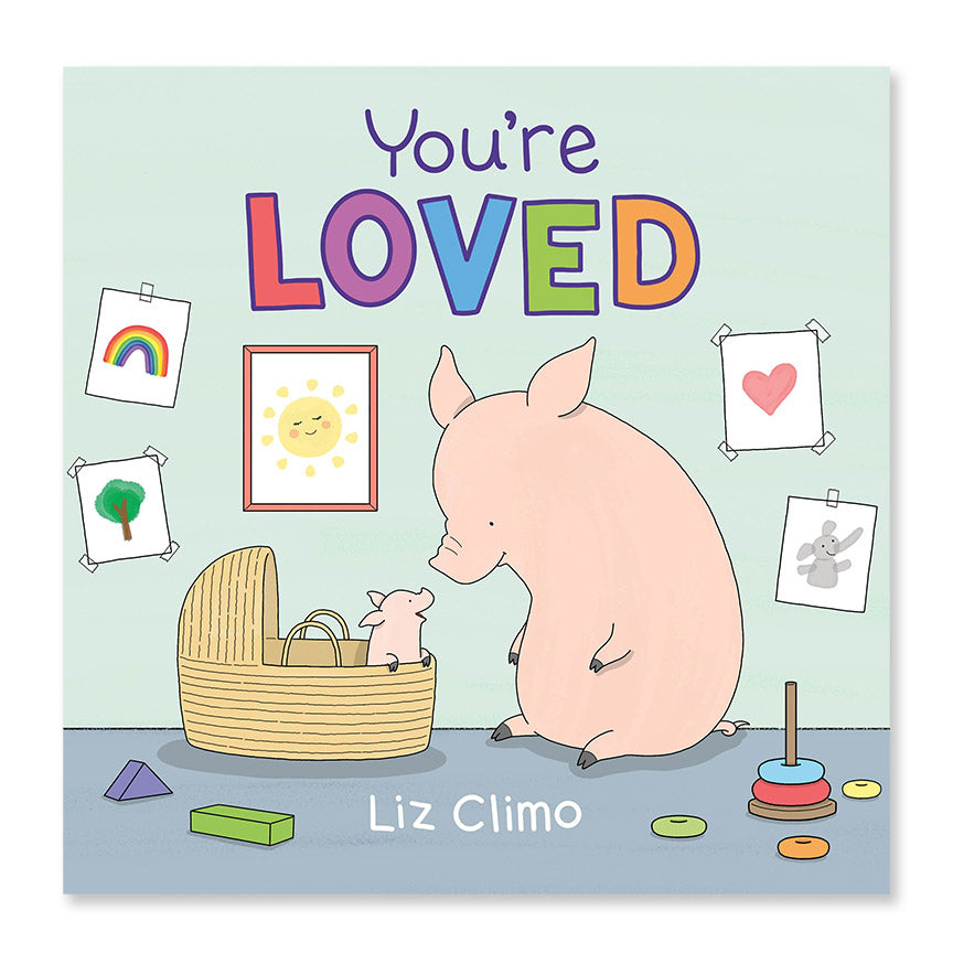 Cover of the book "You're Loved" by Liz Climo, featuring an illustration of a pig and a piglet in a basket with various colorful toys and decorations.