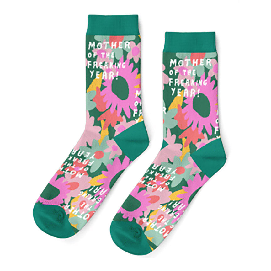 Pair of socks with the text "mother of the freaking year! against a floral background with green toes and trim.